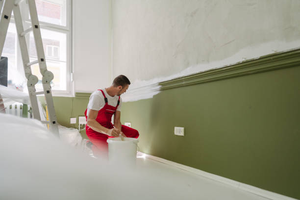 Photo of a professional house painter painting walls in the apartment